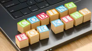 An image of an open laptop with multi colours letter blocks spelling out the phrase coding for kids.