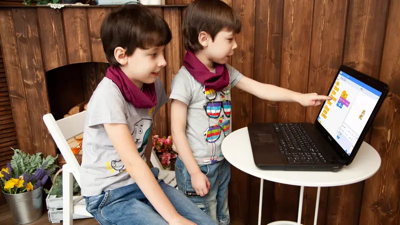Children scratch coding on a laptop together.